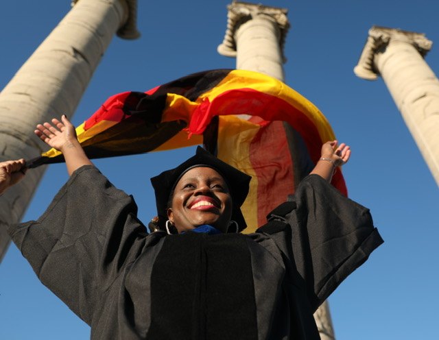 Graduate celebrating outdoors with a flag